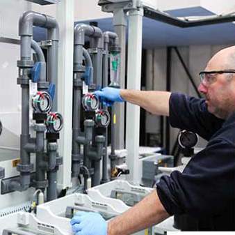 A man adjusts a chemical etching machine